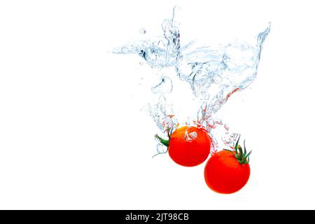 Cherry tomatoes falling underwater with splashes isolated on white background. Stock Photo