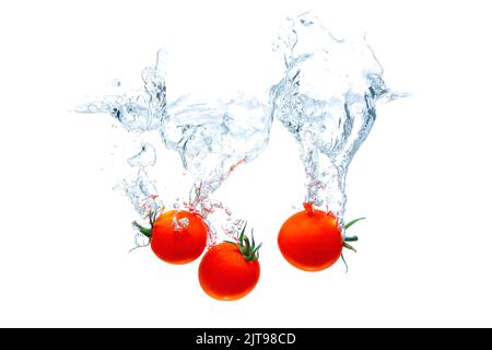 Cherry tomatoes dropped in water with big splashes isolated on white background. Stock Photo