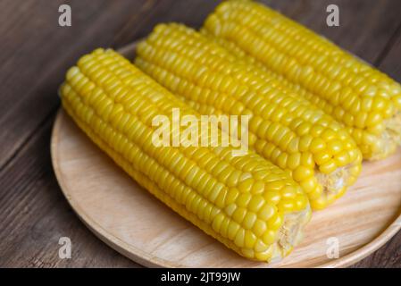 cooked sweet corn on wooden plate background, ripe corn cobs steamed or boiled sweetcorn for food vegan dinner or snack Stock Photo
