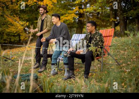 Pleased male friends resting and fishing in nature Stock Photo