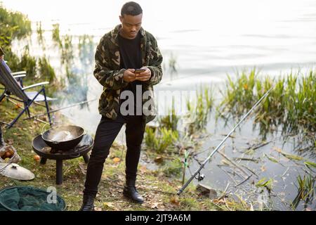 Men using smartphones during resting on pond coast Stock Photo