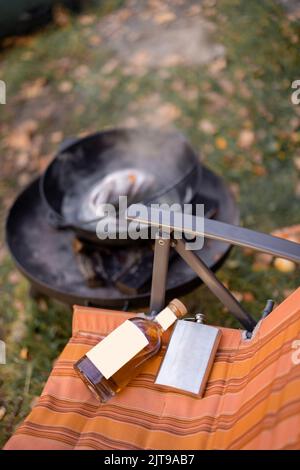 Bottle with strong alcohol and flask on rubber boat Stock Photo