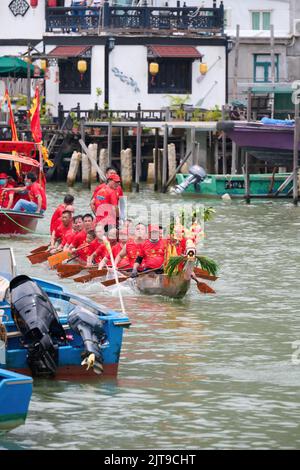 A vertical closeup of people riding on boats at the Dragon Boat Festival in Tai O, Hong Kong Stock Photo