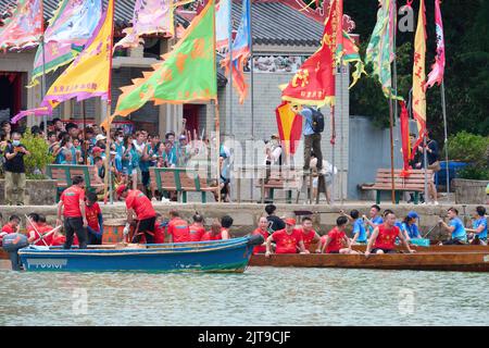 A vertical closeup of people riding on boats at the Dragon Boat Festival in Tai O, Hong Kong Stock Photo