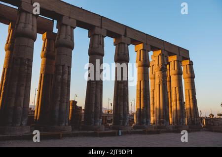 Sunset View to an Illuminated in Yellow Grand colonnade of large Ancient Egyptian temple in Luxor, Egypt Stock Photo