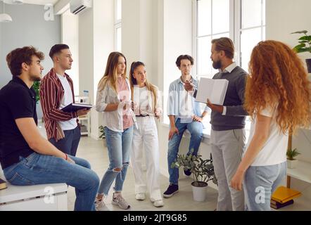 Group of students listening a professor explaining something and showing a book. Stock Photo
