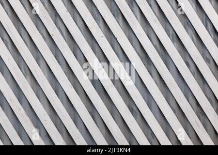 white diagonal wooden planks over gray corrugated metal sheet - flat full-frame background and texture Stock Photo
