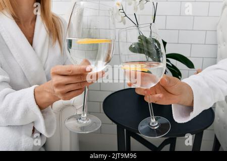 Young couple drinking water with lime from glasses while relaxing in spa to restore their body Stock Photo