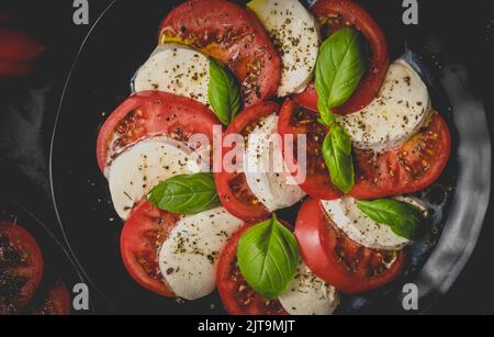 Salads with traditional italian burrata and mozzarella cheese with arugula and tomatoes on dark concrete table with cooking ingredients cherry tomatoe Stock Photo