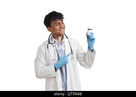 Young peruvian male doctor smiling and pointing at a pill bottle, isolated. Stock Photo