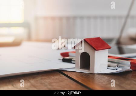 Business, architecture, building and construction concept - Architects house model with measurement tool and blueprints on architect desk Stock Photo
