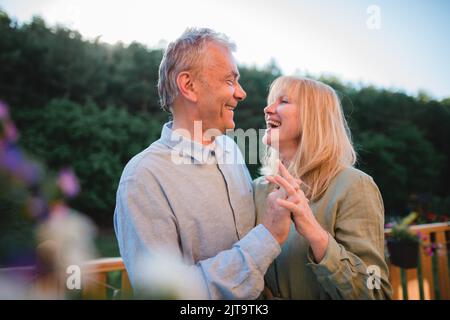 Portrait of affectionate senior couple spending time together and dancing in garden at home. Stock Photo