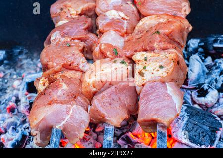 Roast Beef Kebabs On BBQ Grill. Selective focus on raw pork marinated vinegar-pickled meat with spices being cooked on skewers on outdoor wood-fired b Stock Photo