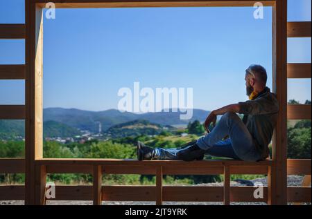 Handyman resting and having break when working on wooden construction site, diy eco-friendly homes concept. Stock Photo