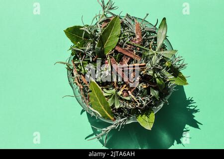 A simple glass bowl of fresh natural potpourri photographed from above an direct sunlight on a plain back ground. The plant materials are mainly fresh Stock Photo