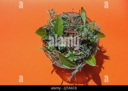 A simple glass bowl of fresh natural potpourri photographed from above an direct sunlight on a plain back ground. The plant materials are mainly fresh Stock Photo