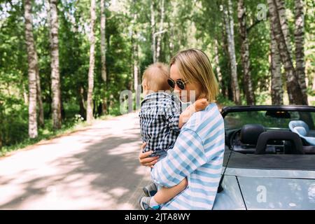 Mom and little son in a convertible car. Summer family road trip to nature Stock Photo