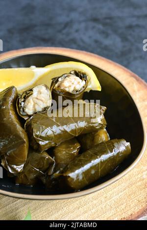 Grape leaf filled with rice served with lemon. Traditional Greek food Stock Photo