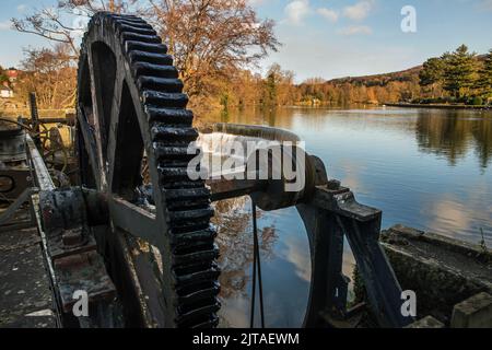 Sluice gate drive wheel and weir on the River Derwent, part of the waterpower system which once drove the cotton mills at Belper, Derbyshire, UK Stock Photo