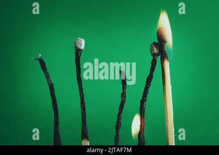 Burnt and bent matchsticks. Wooden matchsticks burning in on a green background. Selective Focus. Stock Photo