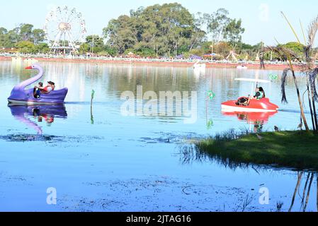City: Marília, São Paulo, Brazil, - July, 03, 2022: Paddle boating or rowing on the lake in Lago with Ferris wheel in the background with Brazilian f Stock Photo