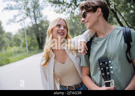 man in sunglasses and blonde woman smiling at each other in countryside Stock Photo