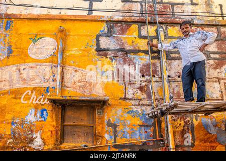 A painter in front of a colorful house, Rajasthan, India Stock Photo