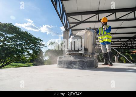 A worker trowelling with power tool on concrete surface at construction site. Concrete floors. Stock Photo