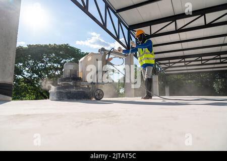 Construction worker using machine polishing surface floor smoothing and finishing hardener or epoxy concrete at construction site. Concrete floors. Stock Photo