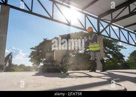 Construction worker using concrete polishing machine or polishing marble floor in modern office building. Man works with grinding machine for floor at Stock Photo