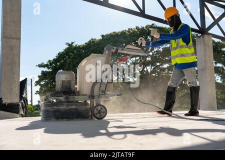 A man wear safety works with grinding machine for concrete floor at construction site. Concrete floors. Stock Photo