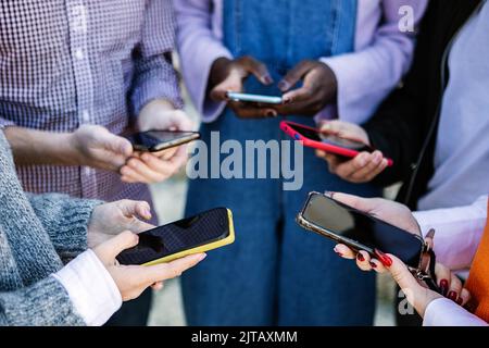 Close up young people hands using mobile phone together Stock Photo