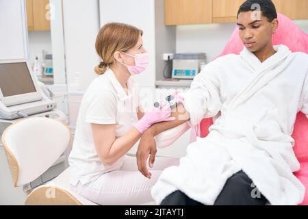 Professional dermatologist examining male patient skin with dermatoscope Stock Photo