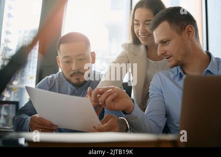 Team of young professionals discussing document in open office Stock Photo