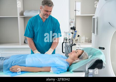 Woman is lying on table tomograph, doctor is standing next to her Stock Photo