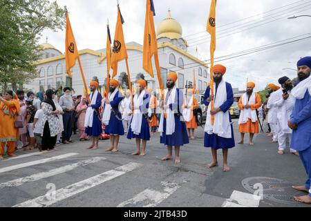 5 Sikh men in blue robes & orange turbans hold flags outside the Sikh Cultural Center. At the start of the Nagar Kirtan parade in Richmond Hil, Queens Stock Photo