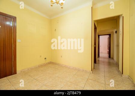 Entrance hall of a residential house with stoneware floors, a long corridor leading to various rooms and light yellow walls Stock Photo
