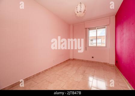 Empty living room in a residential house with stoneware floors and walls painted in various shades of pink Stock Photo