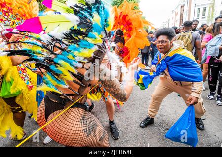London, UK. 29th Aug, 2022. members of the crowd join in with dancers in traditional carnival costumes - Notting Hill Carnival returns after the covid hiatus for August Bank Holiday Monday. It is normally an annual event on the streets of the Royal Borough of Kensington and Chelsea, over the August bank holiday weekend. Credit: Guy Bell/Alamy Live News Stock Photo