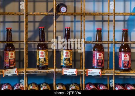Three beers from the Davo brewery in Deventer, one of nine historic Hanseatic towns on the IJssel river, province of Overijssel, Netherlands – "Hang Out", "Café Racer" and "Indie IPA" – stand with tasting-note cards on a shelf made of steel rebar grids in the Davo Shop. Stock Photo