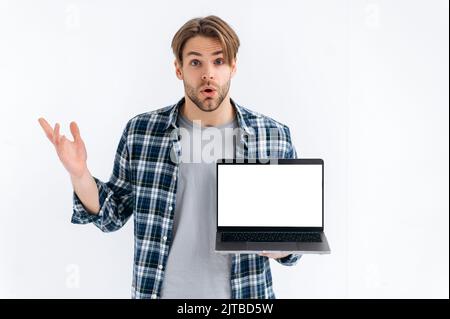 Confused stunned puzzled caucasian guy in casual wear, freelancer or student, holding an open laptop with empty mock-up space, stand on white isolated background, looks at camera in surprised Stock Photo