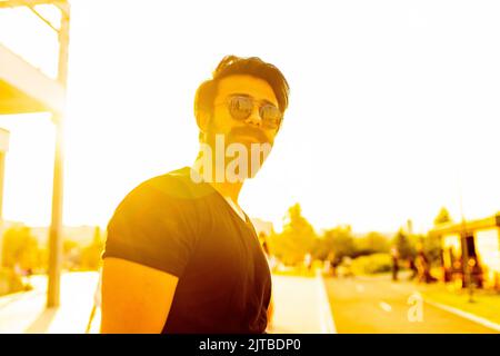 handsome man in sunglasses in summer park at sunset gold lights Stock Photo