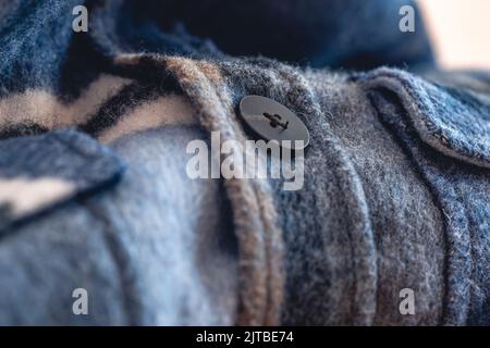 Button on a warm blue shirt, macro shot. Stock Photo
