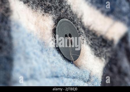 Button on a warm blue shirt, macro shot. Stock Photo