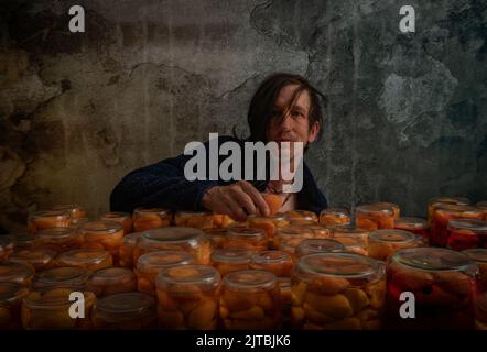 Making of apricot compote on wooden table interior middle of summer in cellar with black hair man Stock Photo