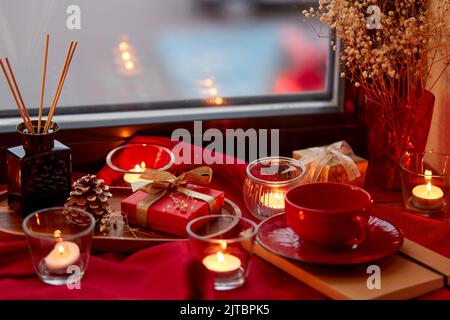 christmas gift, candles and cup on window sill Stock Photo