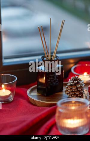 aroma reed diffuser and candles on window sill Stock Photo