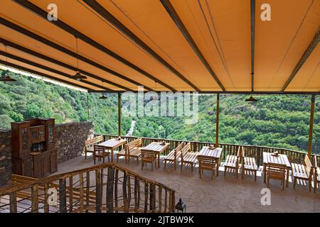Wooden tables and chairs made in an open air restaurant ready to receive guests, with bright tarpaulin roof Stock Photo