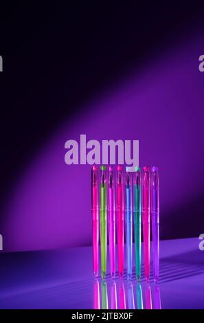 Creative minimal composition made with school supplies flying in the air in neon colors on isolated black background with copy space. Back to school. Minimal, conceptual art. Cyberpunk and cosmos aesthetics. Stock Photo