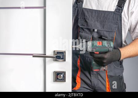 master installs a door lock in the room Stock Photo